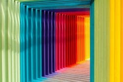 A rainbow colored tunnel leading to a building.