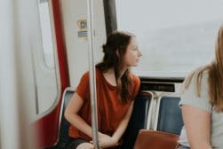 Two women sitting on a train looking at each other.