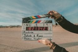 A person holding up a clapper board in the desert.