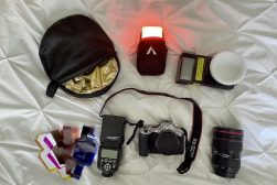 the contents of a camera bag laid out on a bed.