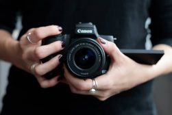 A woman holding a canon eos camera.