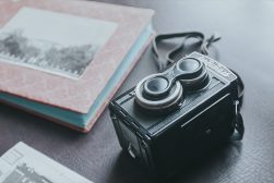 an old camera on a table next to a photo album.