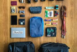 The contents of a travel bag are laid out on a wooden floor.