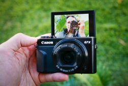 A person holding a camera with a flip screen on it.