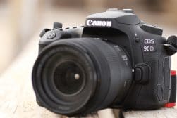 A canon eos dslr sitting on a wooden bench.