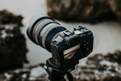 A camera is sitting on a tripod in front of rocks.
