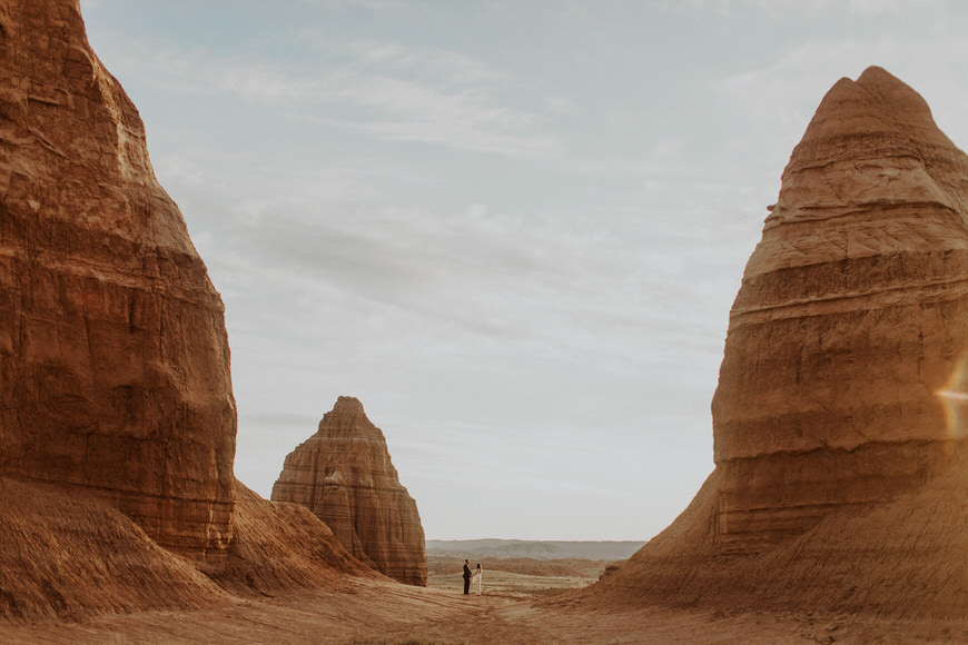 A person walking through a desert with a lot of rock formations.