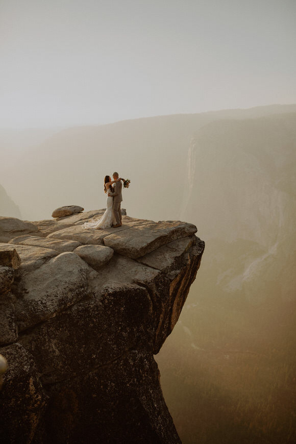 A man and woman standing on a cliff edge.
