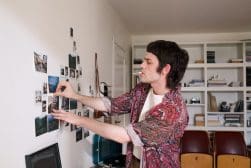 A man putting photos on a wall.