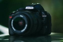 A nikon dslr D3100 camera sitting on a table.