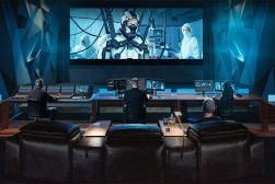 a group of people sitting in front of a large screen.