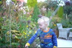 A young boy is playing with a frisbee in a garden.