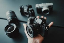 A person's hand holding several different cameras.