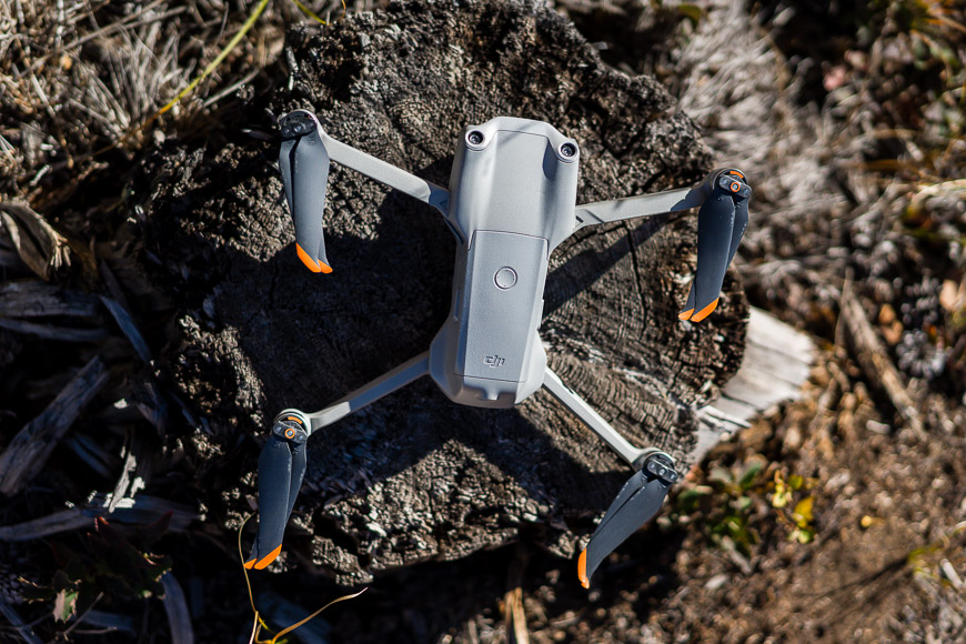 A dji phantom quadcopter sitting on top of a tree stump.