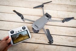 A person is holding a dji drone next to a tablet.