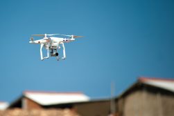 a white drone flying over a building.
