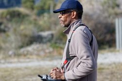 a man wearing a hat and carrying a drone-controller.