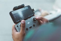 A person holding a smartphone and a drone.