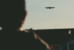 A person looking at a drone flying in the sky.