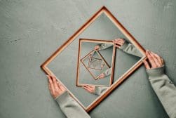 A person holding a mirror with a square in it.