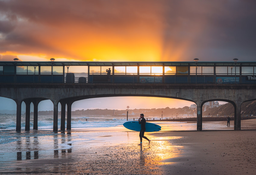 A person walking on the beach with a surfboard.