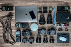 A collection of camera equipment laid out on a wooden floor.