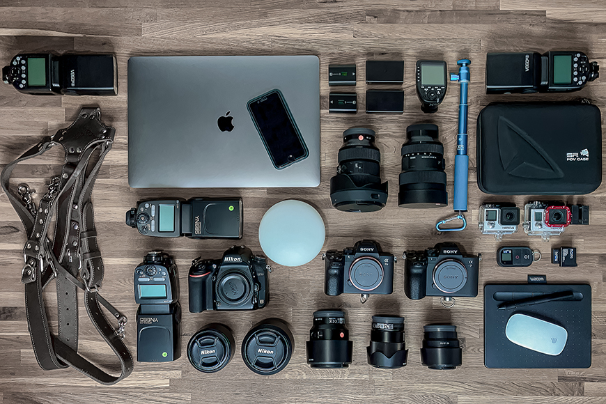 A collection of camera equipment laid out on a wooden floor.