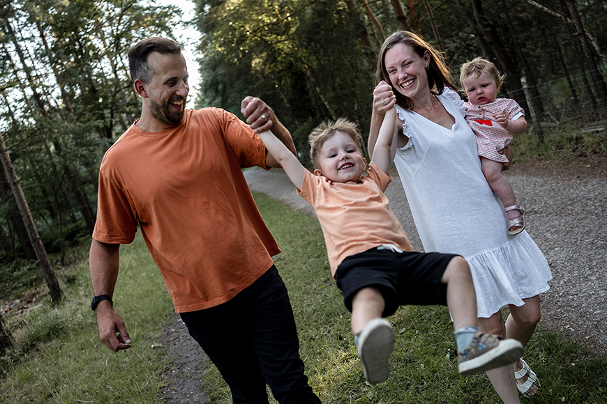 A family is walking down a path in the woods.