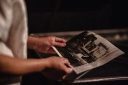 A man is holding an old photograph in front of a stove.