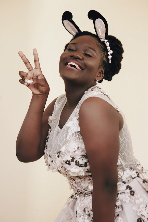 A woman smiling and holding up peace sign.