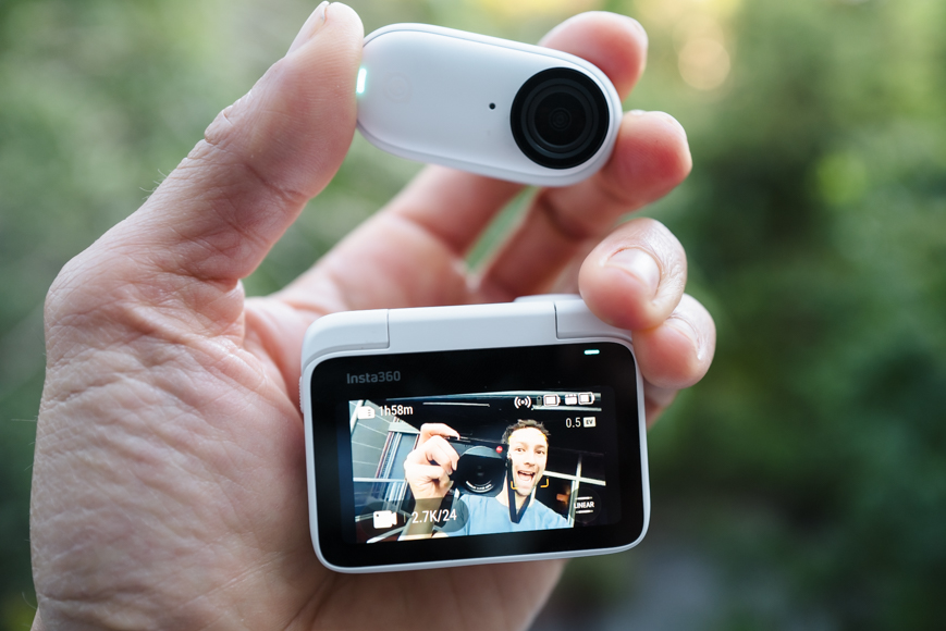 A person holding up a small camera with a person's face on it.