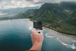 A person holding a gopro camera over the ocean.