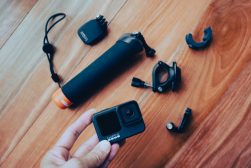 a person holding a gopro camera next to various accessories.