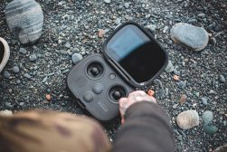 a person holding a black drone on a rock.