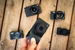 A person holding a camera with several other cameras in front of it.
