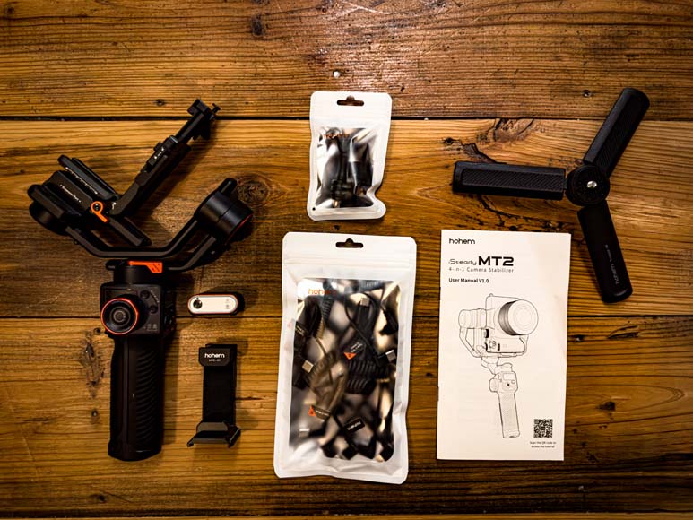 Hohem iSteady MT2 gimbal with accessories on wood floor.