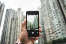A person is taking a picture of a building with tall buildings in the background.