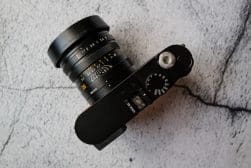 A black camera with a lens sitting on top of a concrete surface.
