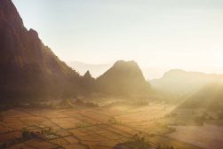 an aerial view of a valley with mountains in the background.