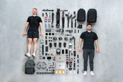Two men standing in front of a pile of camera equipment.