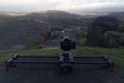 A camera sits on a slider in front of a mountain.