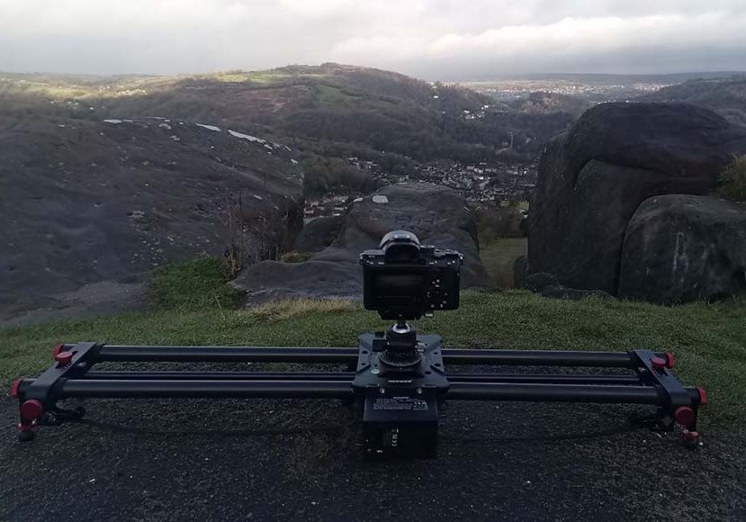 A camera sits on a slider in front of a mountain. A camera sits on a slider in front of a mountain.