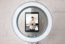 A lighted mirror with a tablet on it.