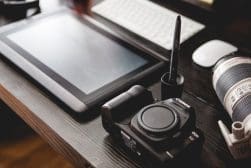 A desk with a tablet, camera, and other items.