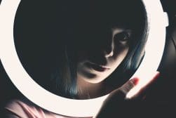 A woman with blue hair is holding a lighted ring.