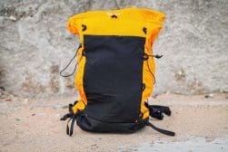 An orange and black backpack sitting on the ground.
