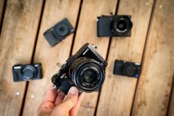 A person holding a camera in front of a group of other cameras.