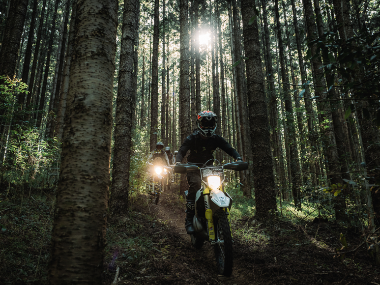 A person riding a dirt bike through a forest.