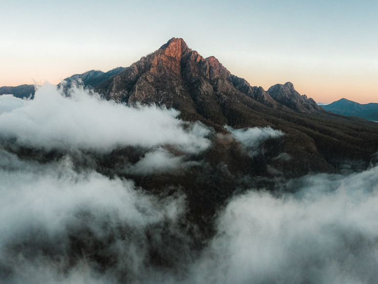 An aerial view of a mountain covered in clouds.