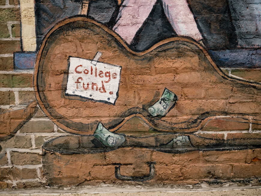 A painting of a guitar on a brick wall.